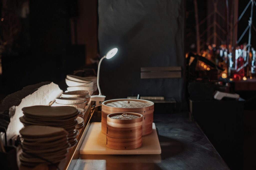 A warm and ambient kitchen scene featuring bamboo steamers illuminated by a lamp.